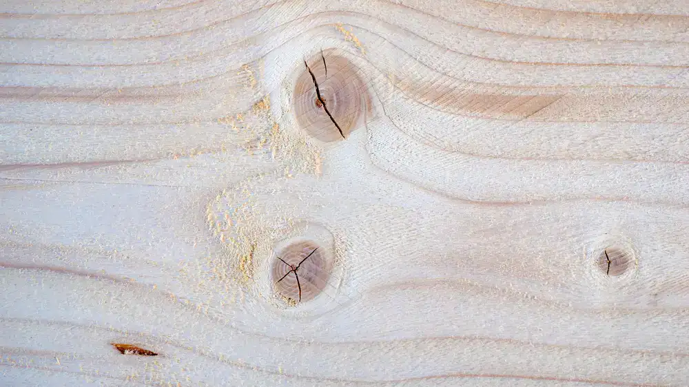 Planos y muestras de madera sobre una mesa de taller